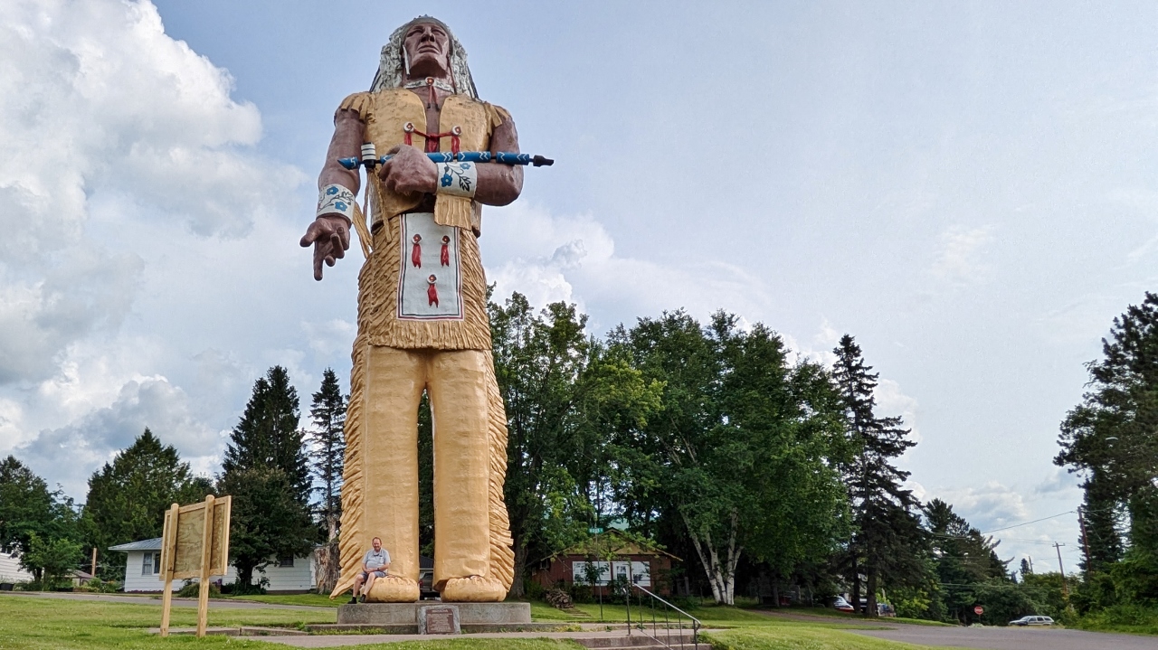 Bill is Sitting on Toe of  52 Foot Tall Hiawatha Statue